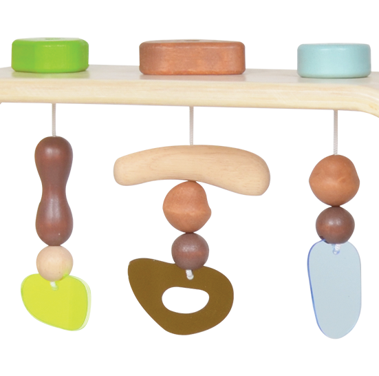 A wooden baby gym with dangling toys in various shapes, including a bear and a carrot, with a green sandglass and brown accents.