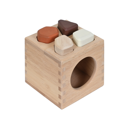 A wooden sound stones sorter box with four colorful irregular shaped pieces inside.