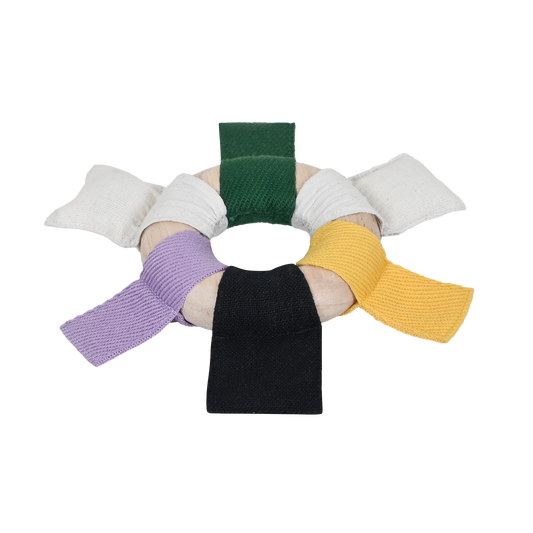 A circular ribbon ring with alternating black, white, and green ribbons attached to it. Each ribbon is a different color and the ring is smooth and wooden.