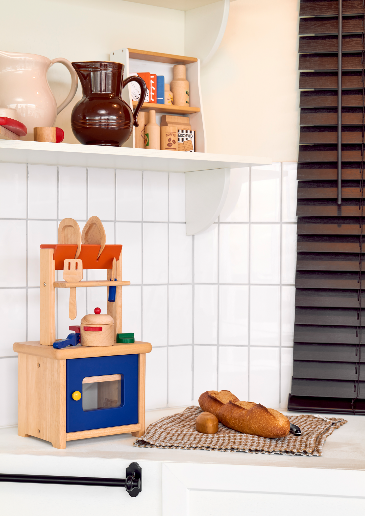 A wooden stall with various wooden and plastic food items displayed on shelves, including boxes of fake sugar and coffee, a bottle of olive oil, and cartons of pretend pasta and coffee.
