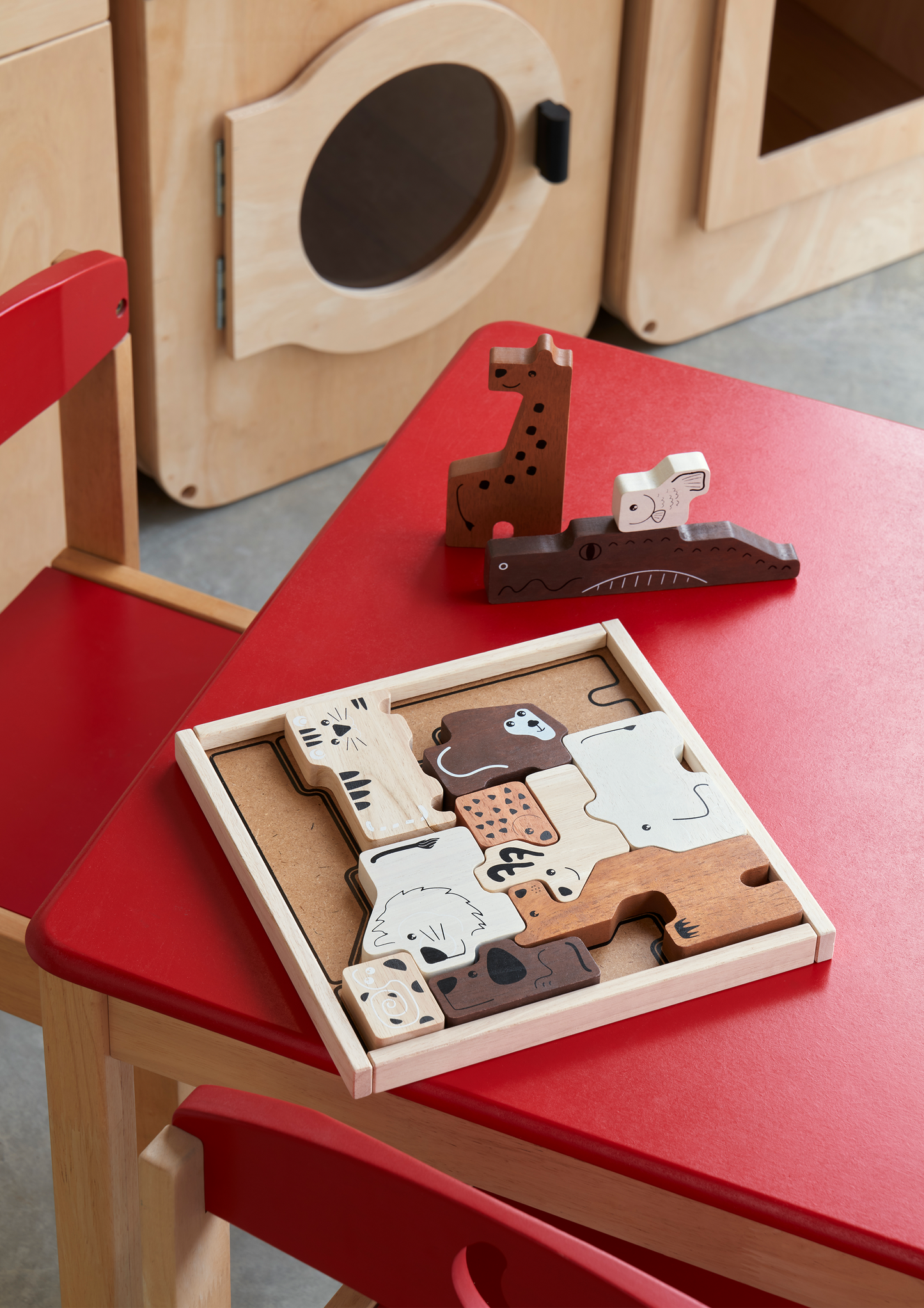 A small wooden desk with a red paper roll holder and a matching chair, designed for children.