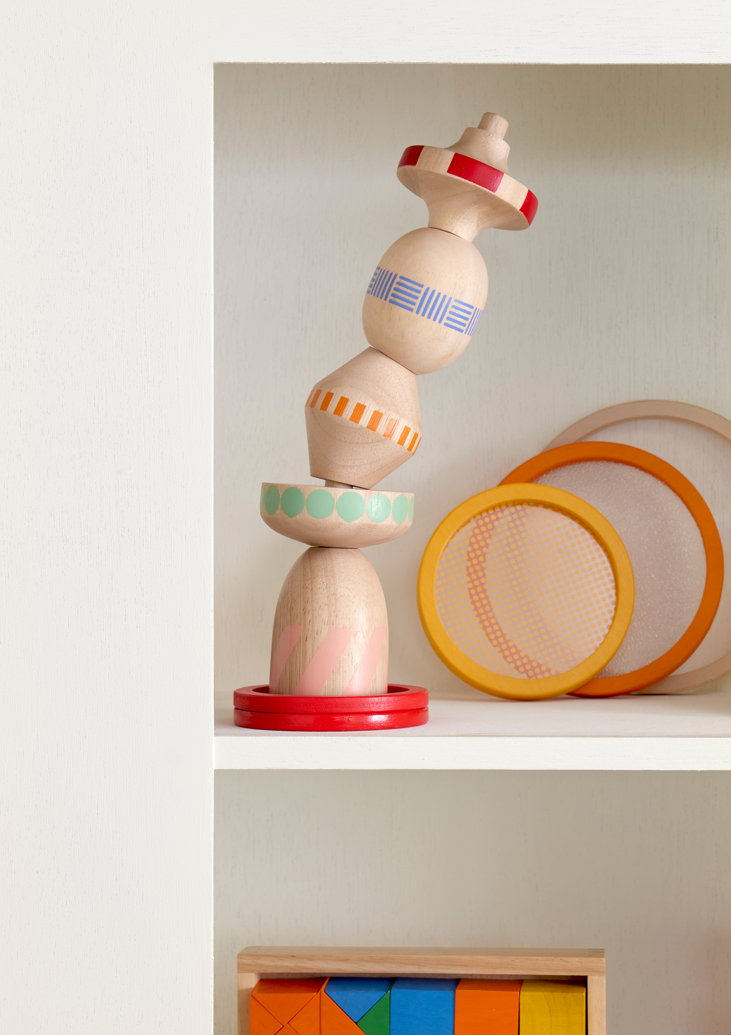 A colorful wooden stacking toy with five revolved blocks of different sizes and weights, arranged in a stack.