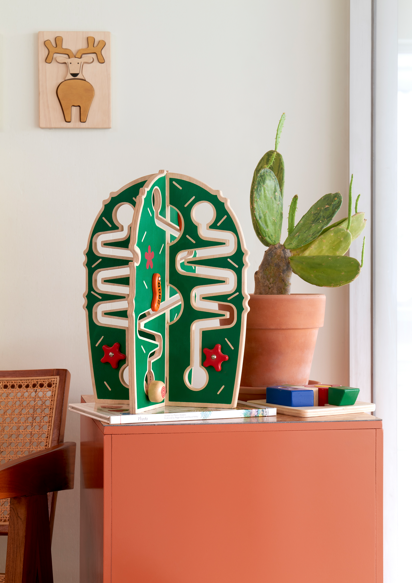 A green rolling cactus-shaped toy with marbles on tracks