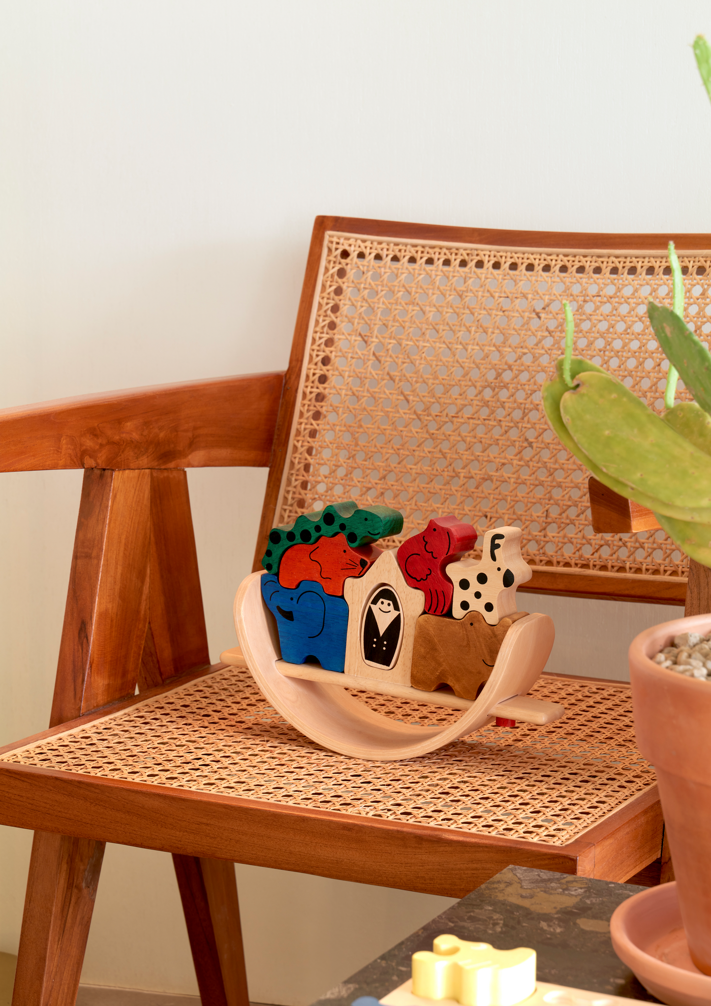 A colorful wooden balance toy in the shape of a boat with animals and a person figurine.