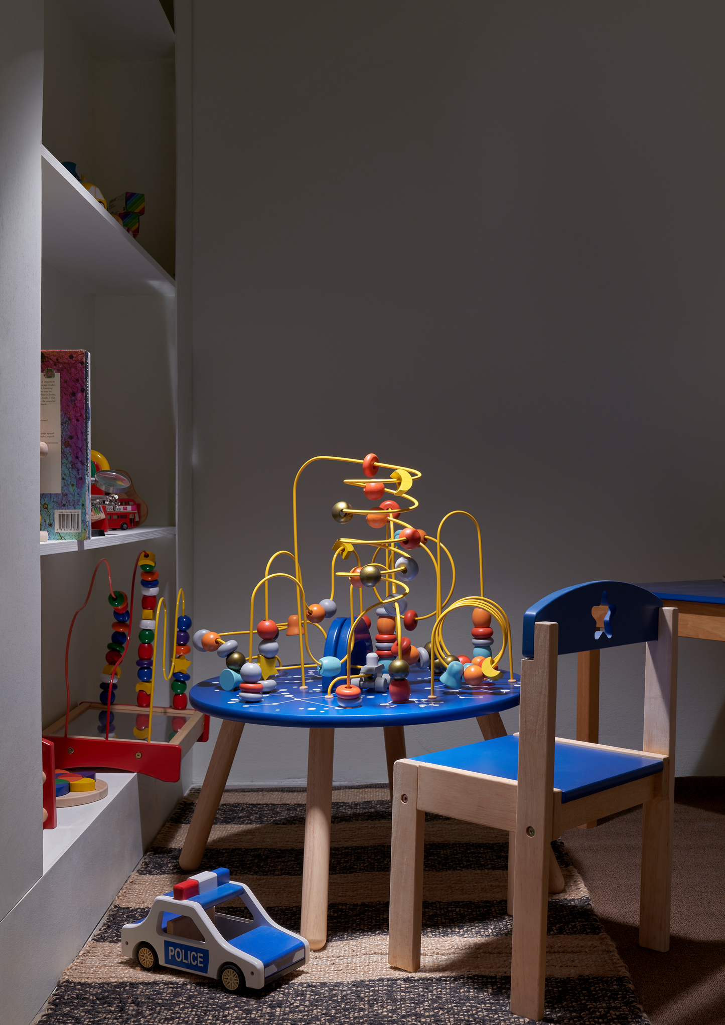 A toy police car with opening cab roof and two dolls inside, predominantly blue and white with red accents.