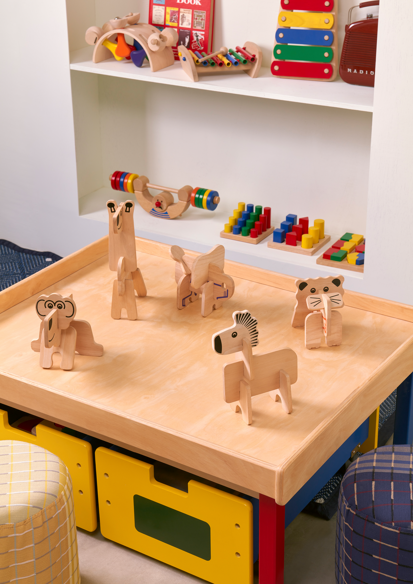 A colorful wooden balance man toy with red, orange, yellow, green, blue, and purple weight plates on a wooden board with a central character illustration.