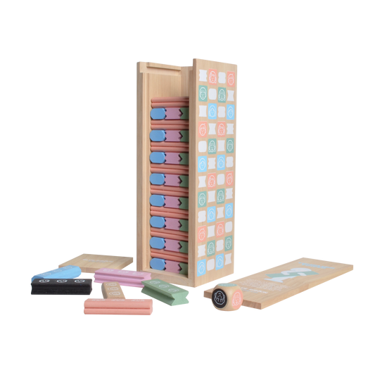 The image shows a wooden tumbling tower game with various colored wooden blocks and a wooden box packaging. A dice is also visible to the side.