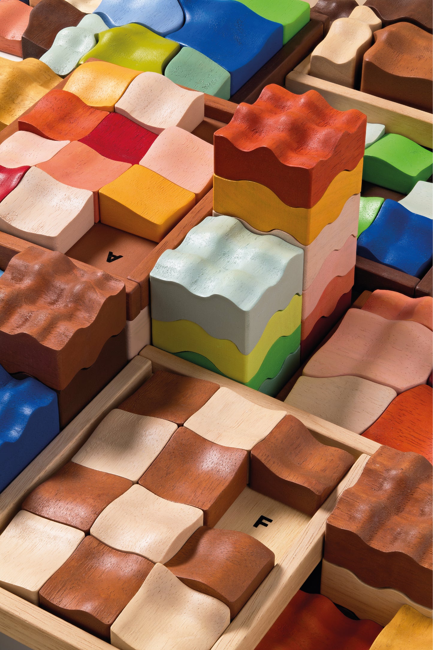 A stack of colorful geometric shaped blocks representing a rammed earth tower, with some blocks displayed both in and out of position, indicating a puzzle or building set.