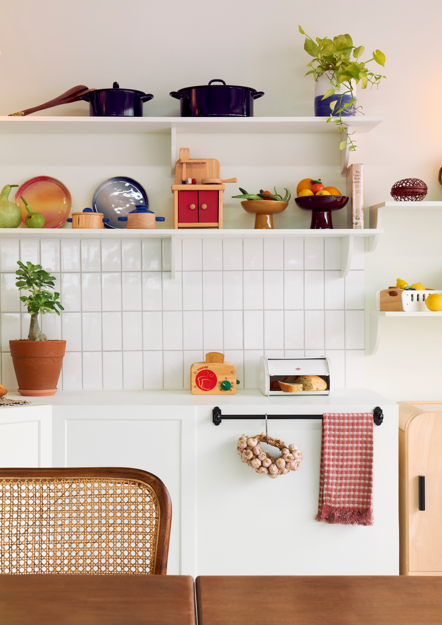 A wooden play toaster with slots for bread and a green twisty dial, designed for children.