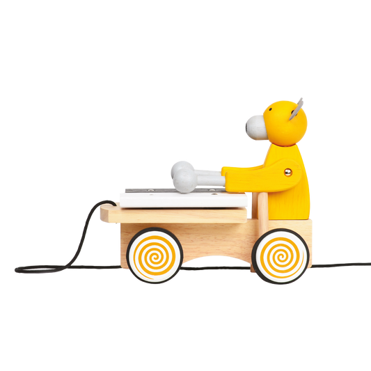 A colorful toy xylophone in the shape of a cartoon bear with yellow body and black hair, attached to a wooden structure resembling a stomach and intestines, on a spiral-patterned base.