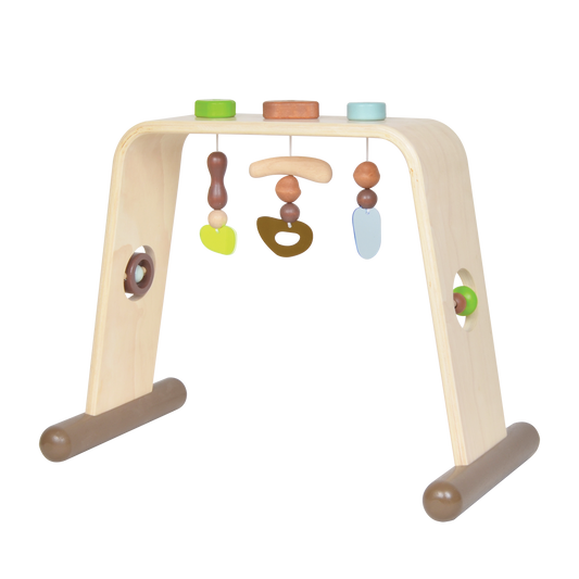 A wooden baby gym with dangling toys in various shapes, including a bear and a carrot, with a green sandglass and brown accents.