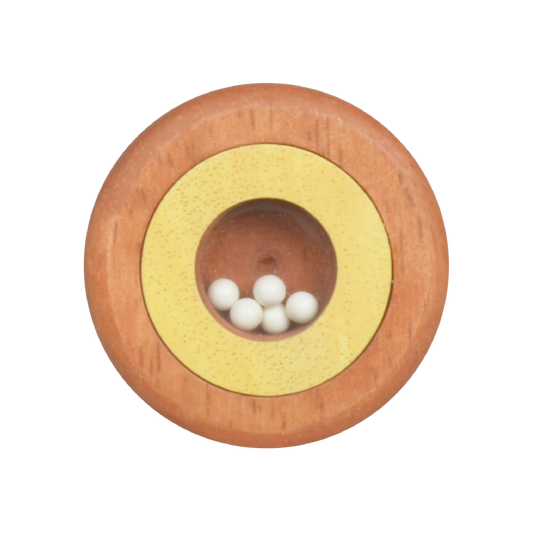A round maraca with a wooden base and white beads in the center, with a yellow and red design around the beads.
