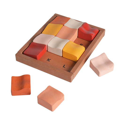 A set of square wooden tiles in various shades of red, orange, and beige, some with letters 'K' and 'L' marked on them, presented on a wooden surface with a few tiles off to the side.