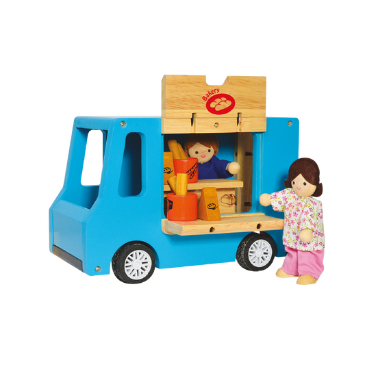 A blue toy bakery truck with a wooden counter and a doll representing a customer, as well as a doll baker, inside the truck.