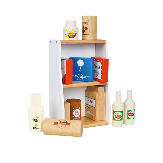A wooden stall with various wooden and plastic food items displayed on shelves, including boxes of fake sugar and coffee, a bottle of olive oil, and cartons of pretend pasta and coffee.