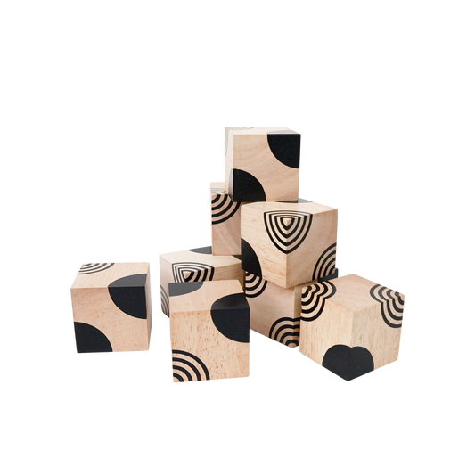 A set of wooden cubes with black geometric patterns on each, arranged in a pile.
