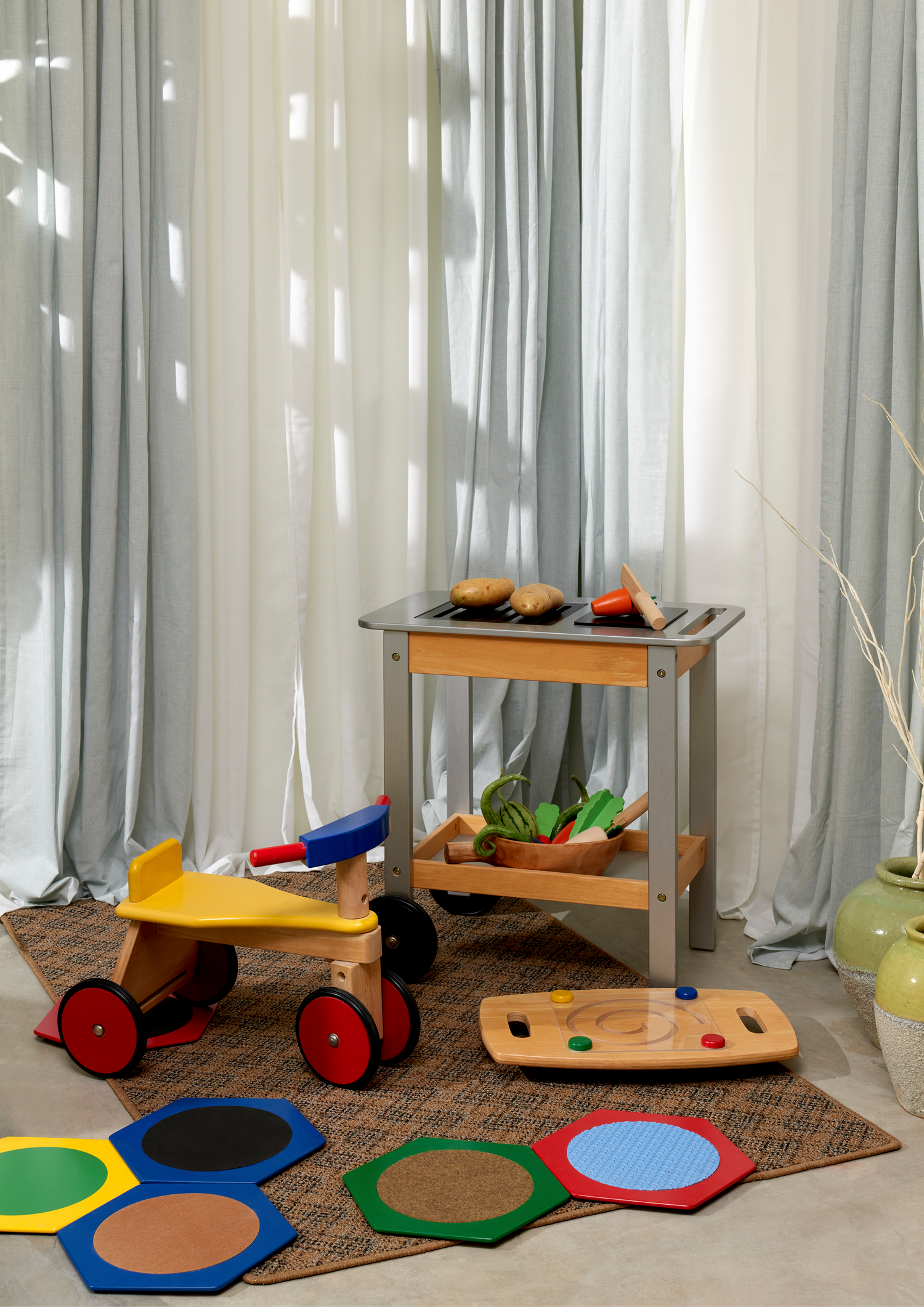 A set of wooden vegetables in different colors including orange, purple, red, brown, and white, with a wooden knife. Each vegetable is attached to a wooden stick.